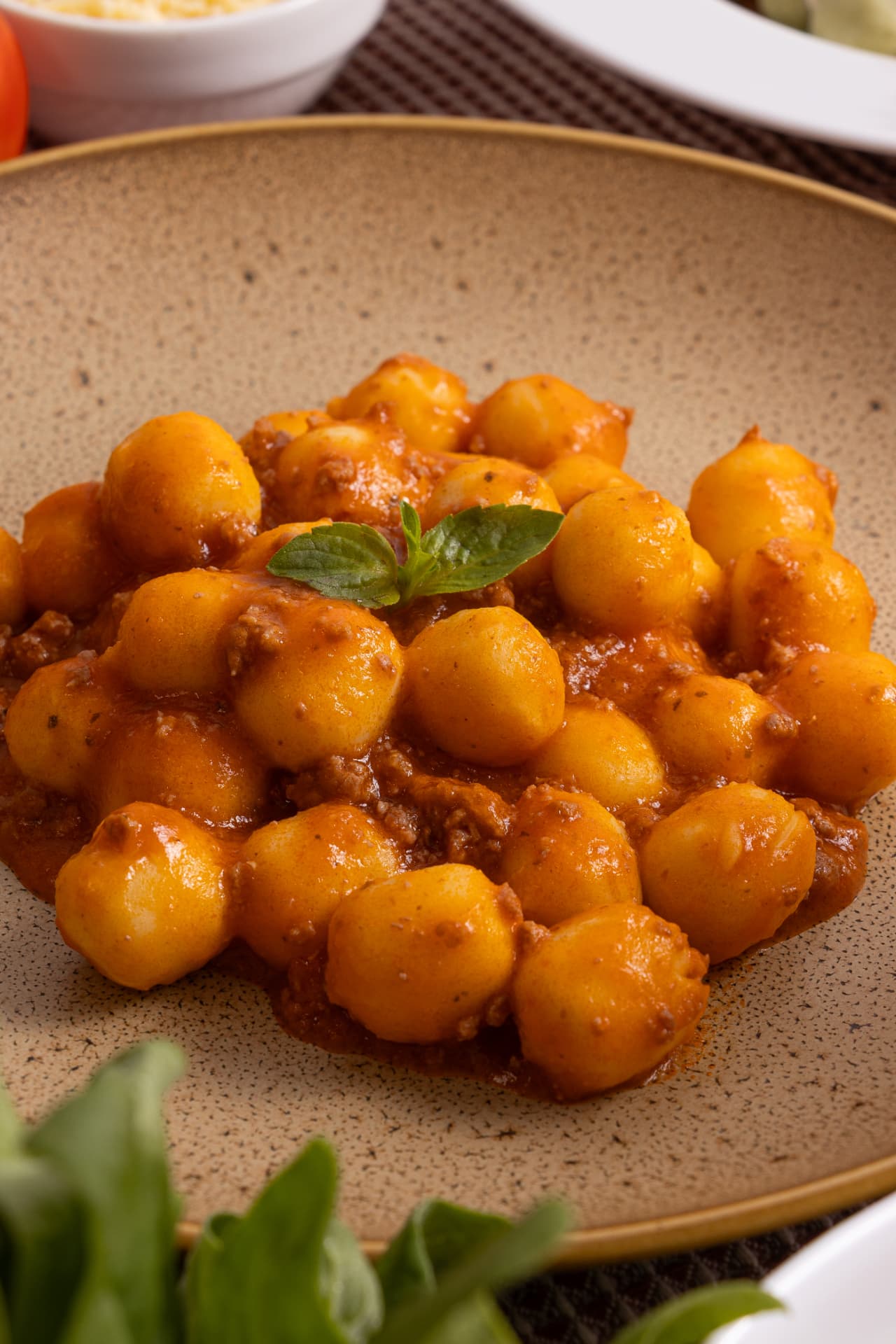Prato de nhoque de batata ao molho bolonhesa com manjericão
