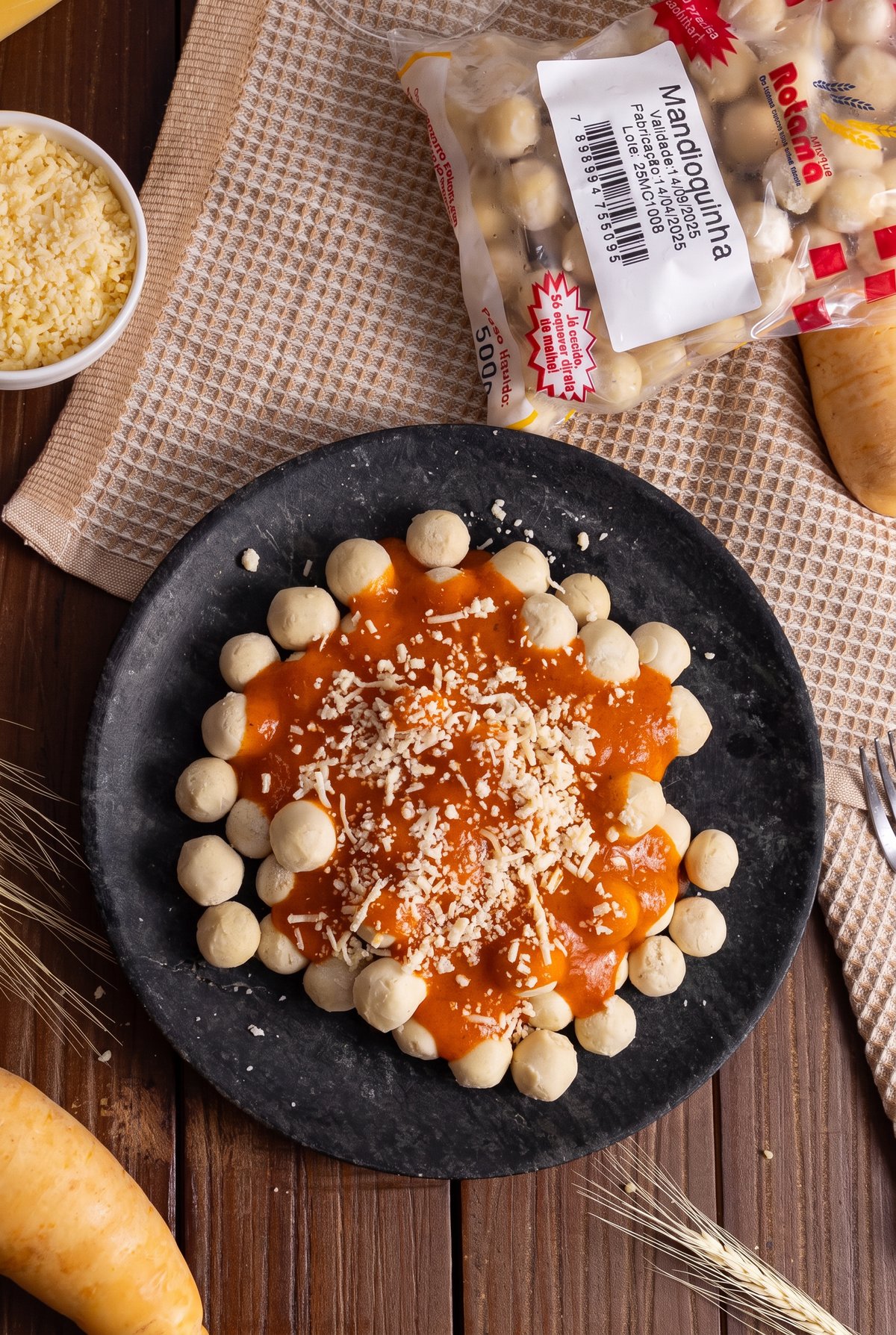 Nhoque de mandioquinha com molho de tomate e queijo em prato de pedra